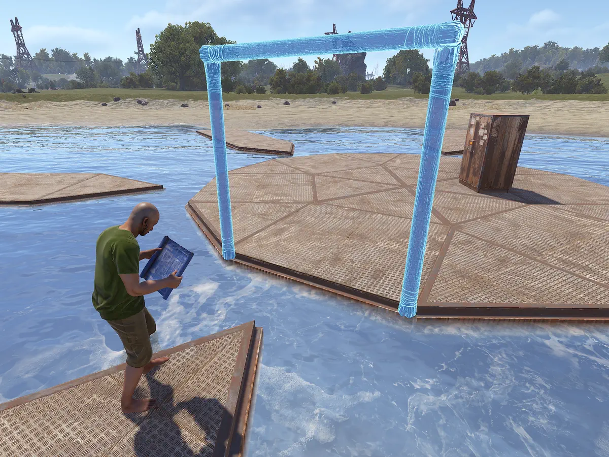 A player in a build session holds a building plan beside a half-built base: floors on the water, a wall frame going up and a tool cupboard.